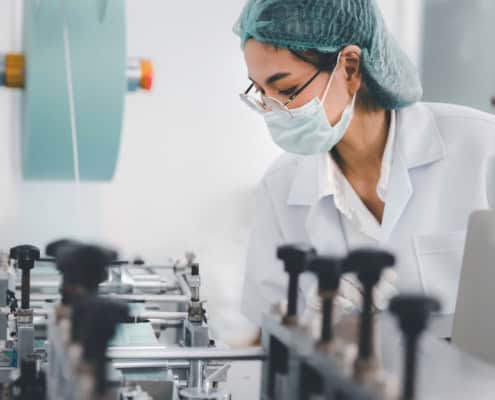 Asian female doctor or engineer working at clean medical mask production factor